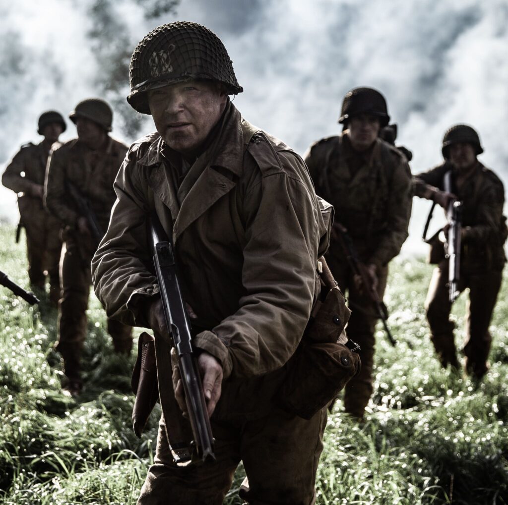 Captain Bobby Brown leads his men across a field under the cover of smoke. (Dramatic Recreation) Jason Johnson