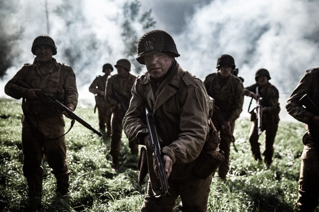 Captain Bobby Brown leads his men across a field under the cover of smoke. (Dramatic Recreation)L-R: Roman Anthony, Jason Johnson, Nathan Plumite