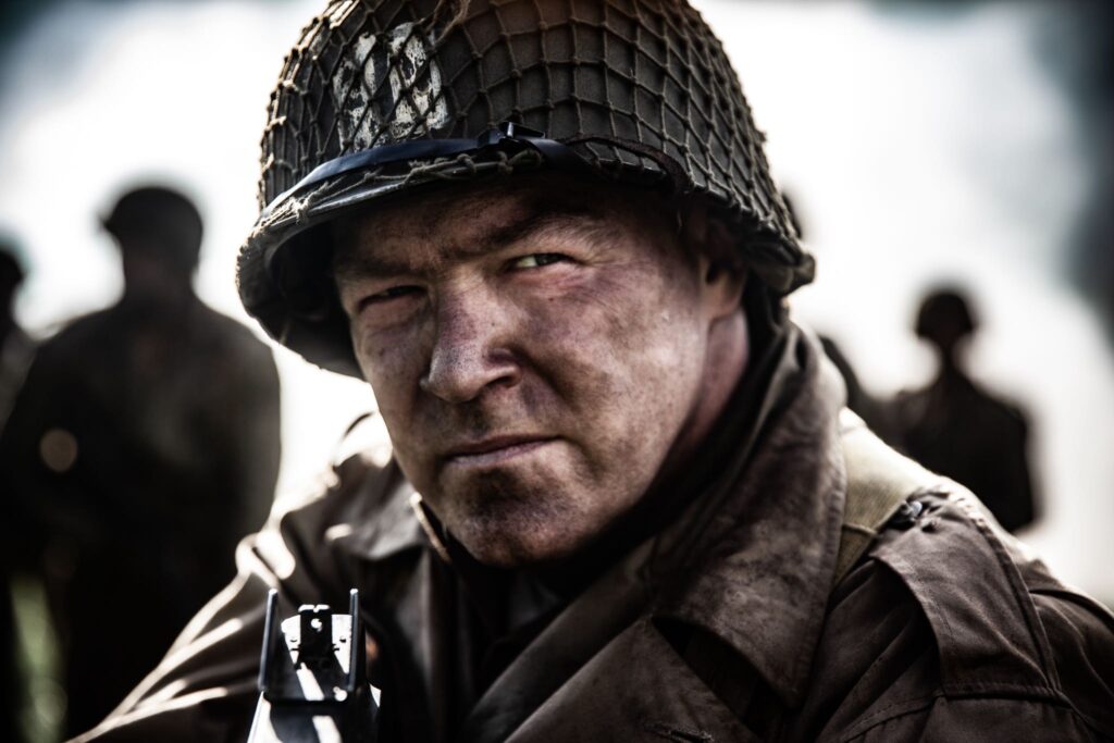 Captain Bobby Brown leads his men across a field under the cover of smoke. (Dramatic Recreation) Jason Johnson