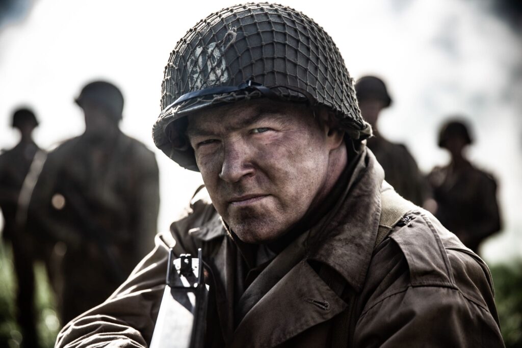 Captain Bobby Brown leads his men across a field under the cover of smoke. (Dramatic Recreation) Jason Johnson