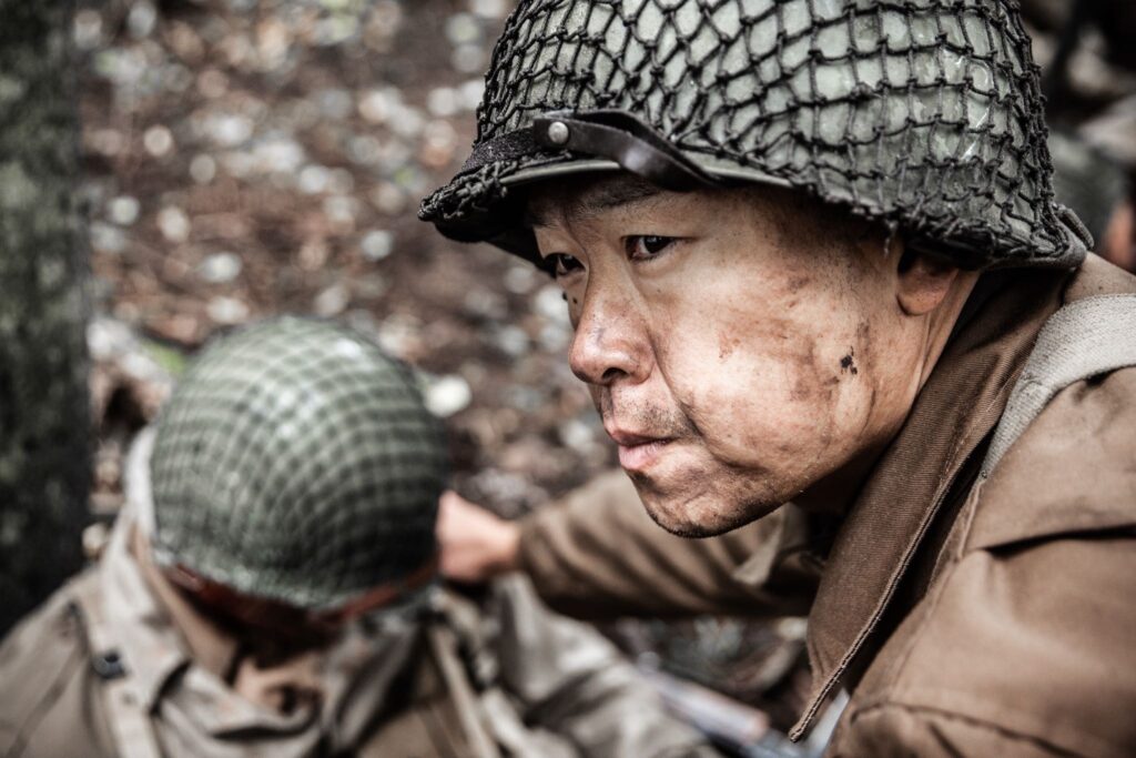 Sergeant Shiro Kashino assists a wounded soldier after a German artillery attack. Dramatic Recreation) Alex Law