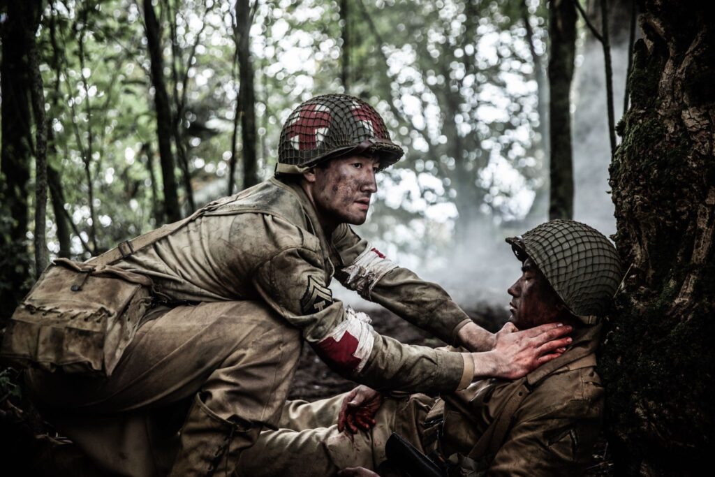 An American Medic applies pressure to Private Onaga's bullet wound. (Dramatic recreation) L-R: Gabriel Prevost, Sei Campbell