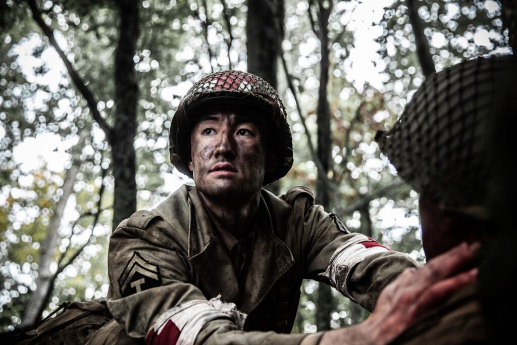 An American Medic applies pressure to Private Onaga's bullet wound. (Dramatic recreation) L-R: Gabriel Prevost, Sei Campbell