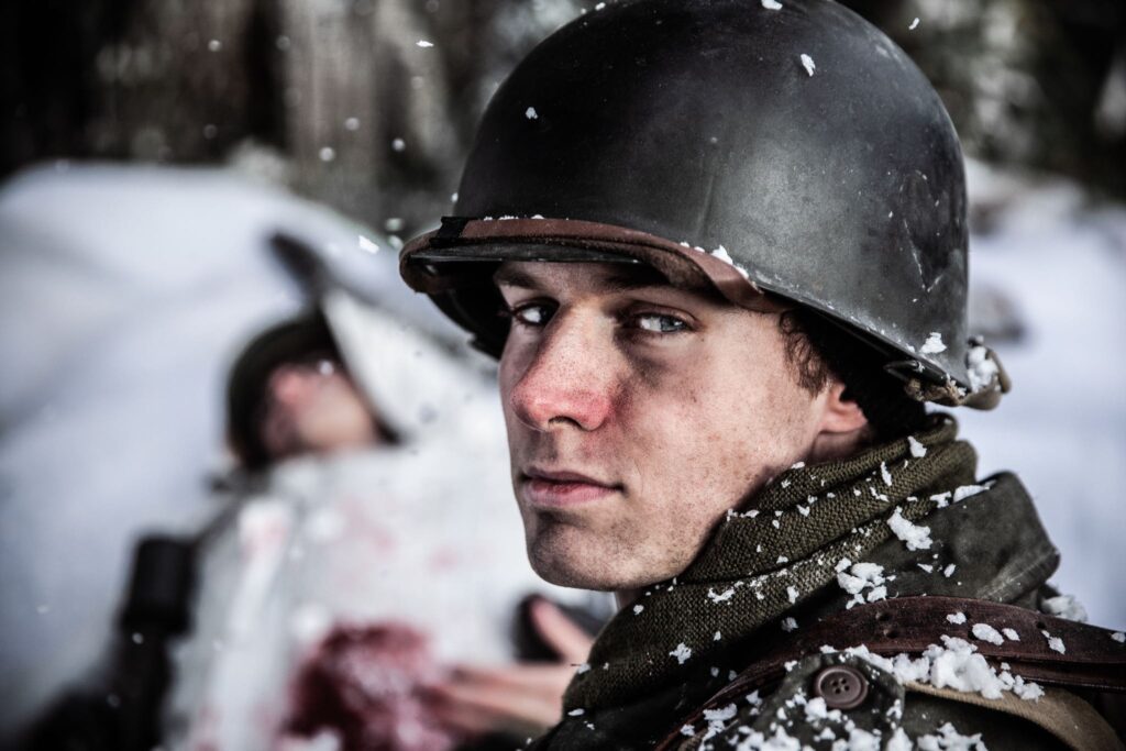 Private First Class Melvin Biddle, a scout in the 517th Parachute Infantry Regiment, stands over a German soldier wounded when he attacked a MG Nest in the forest outside of Hotton. (Dramatic Recreation). Mitch Nel.