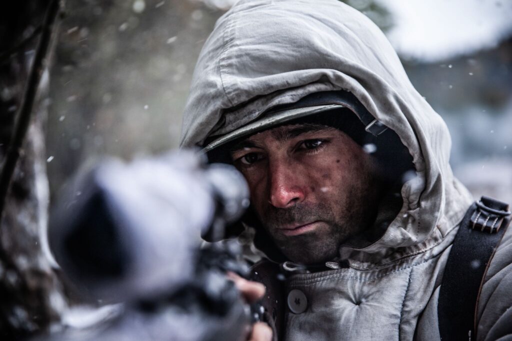 A German sniper in white camouflage, takes aim with his rifles in the forest outside Hotton, Belgium. (Dramatic Recreation) TJ Mathews.