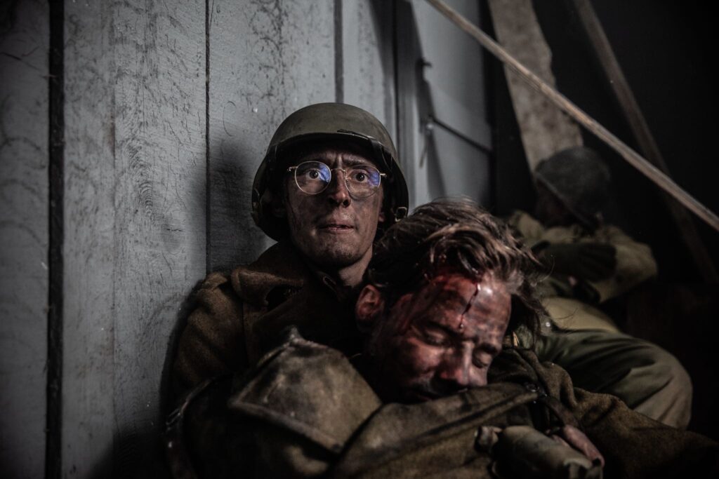 Private First Class Vito Bertoldo pulls his wounded assistant to safety after an attack on their position in Hatten, France. (Dramatic Recreation). Devin Kotlowsk and Boris Bilic