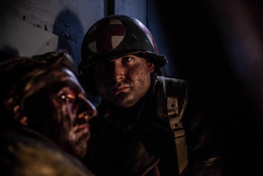 242nd Infantry Regiment Medic tends to Captain William Corson's wounds in Pillbox 9 of the Maginot Line. (Dramatic Recreation). Ivan Sadovsky and Reece Presley