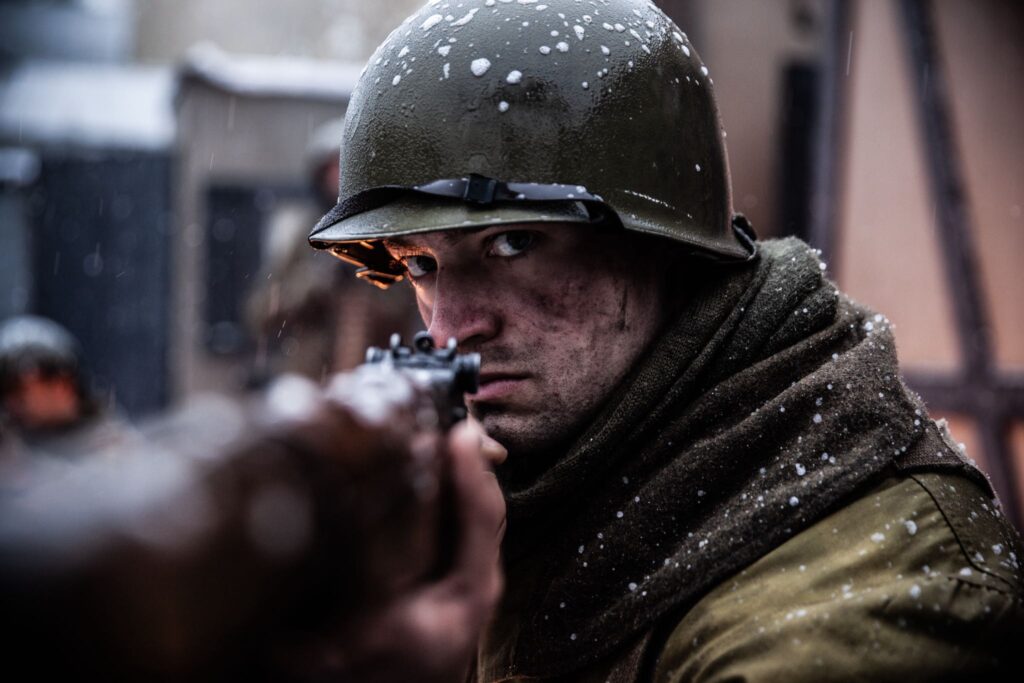 A 242nd Infantry Regiment Soldier aims his rifle while defending Hatten, France. (Dramatic Recreation). Elliot Wesley.