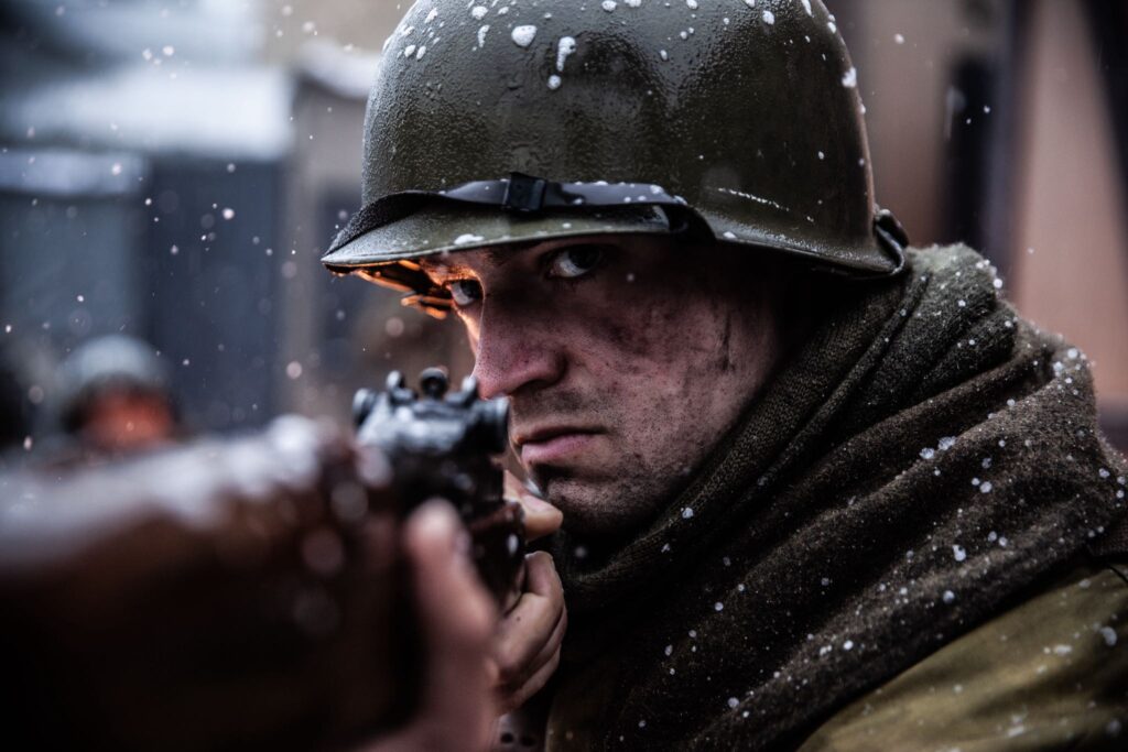 A 242nd Infantry Regiment Soldier aims his rifle while defending Hatten, France. (Dramatic Recreation). Elliot Wesley.