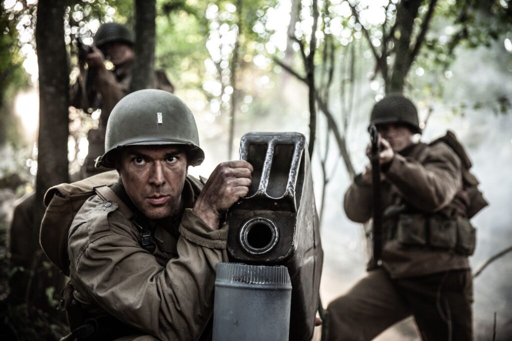 Lieutenant Harris Neil pours gasoline into the German bunker through the venitlation shafts. (Dramatic Recreation) (L-R: Jonathan Woodhall, Kyler Fagan)